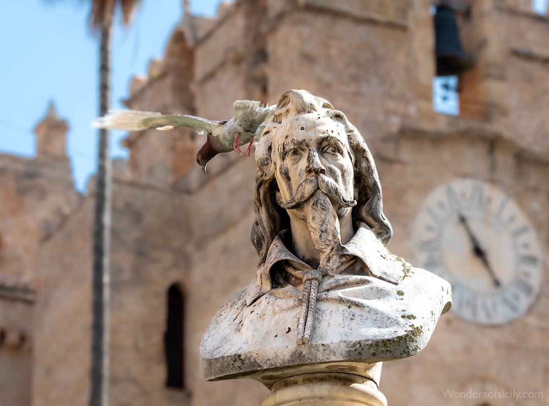 pigeon is seen mid-flight as it departs from a bust of Pietro Novelli